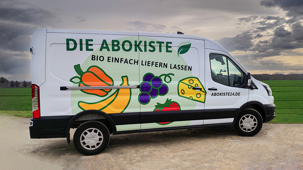 KI generiert: Ein Lieferwagen mit Werbemotiv für Bio-Produkte, Text: "DIE ABOKISTE BIO EINFACH LIEFERN LASSEN".