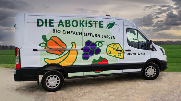 KI generiert: Bio-Lieferdienst "Die Abokiste" mit buntem Gemüse-Design auf einem Transporter. Text: "DIE ABOKISTE BIO EINFACH LIEFERN LASSEN ABOKISTE24.DE"