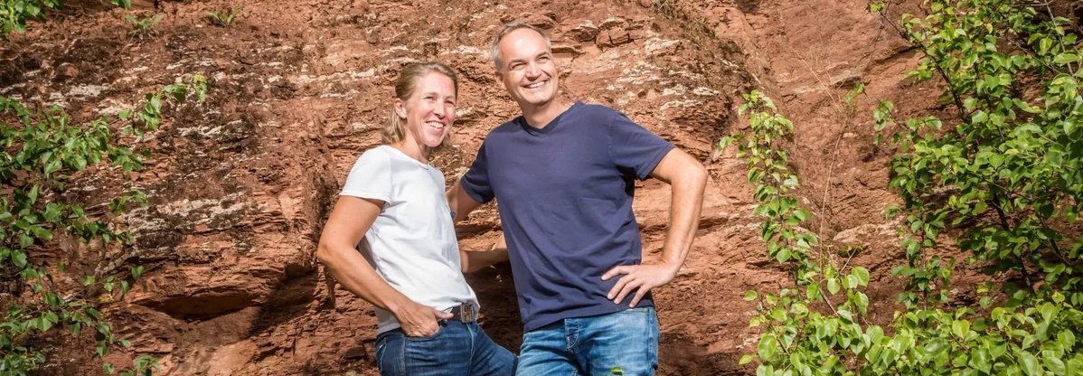 KI generiert: Ein Mann und eine Frau posieren fröhlich vor einer Felswand mit grünen Pflanzen.