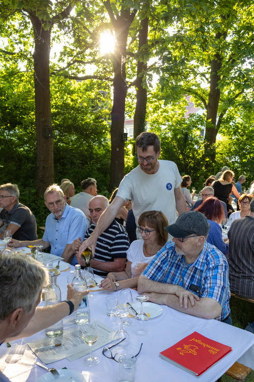 KI generiert: Ein Mann schenkt Wein bei einer Outdoor-Veranstaltung ein.