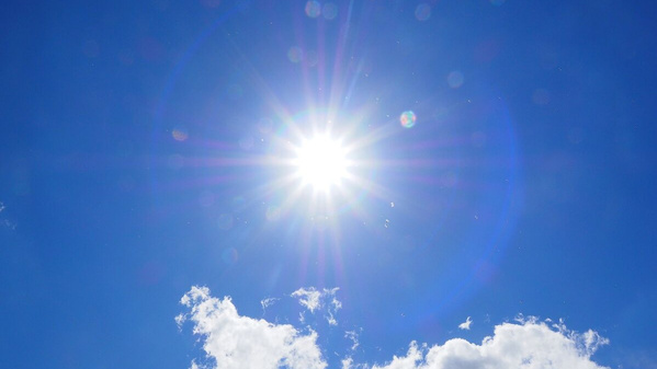 KI generiert: Strahlende Sonne am blauen Himmel mit wenigen Wolken.