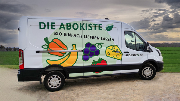 KI generiert: Ein Lieferwagen mit Obst- und Gemüseaufdruck. Text: "DIE ABOKISTE BIO EINFACH LIEFERN LASSEN"