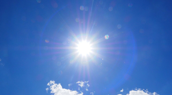 KI generiert: Sonne strahlt intensiv am klaren blauen Himmel mit wenigen Wolken.