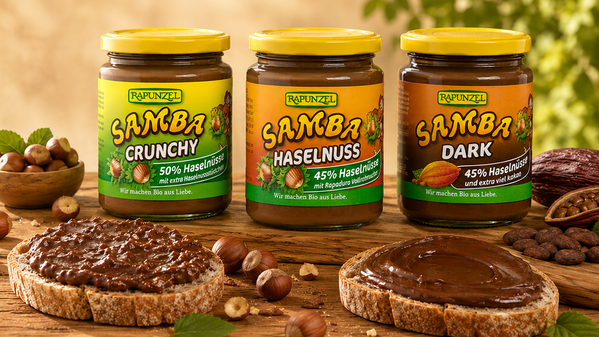 KI generiert: Drei Gläser Rapunzel-Nussaufstrich (Crunchy, Haselnuss, Dark) mit Brotscheiben und Haselnüssen. Text nicht vorhanden.