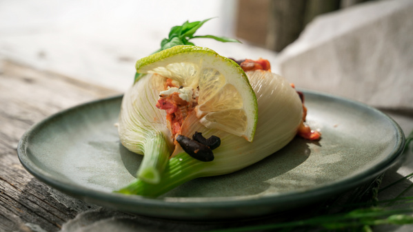 KI generiert: Das Bild zeigt eine appetitliche Tarte, die mit roten Zwiebeln, Walnüssen und Kräutern belegt ist. Daneben liegen Zutaten wie rote Zwiebeln und Kartoffeln auf einem rustikalen Holztisch.