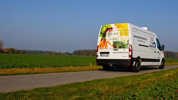 KI generiert: Ein Lieferwagen auf einer Landstraße wirbt für "Bio mit Service!" und abokiste24.de.